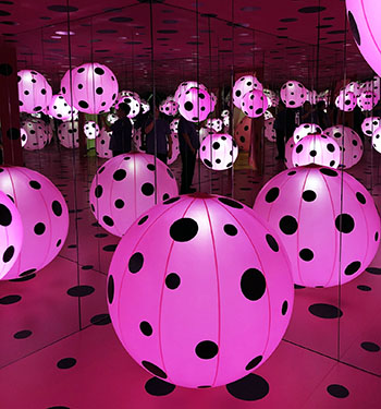 Jason inside Yayoi Kusama featuring pink polka dotted baloons and infinity mirrors